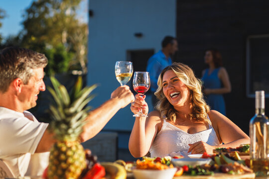 Group of adult friends having diner by swimming pool in sunny backyard. - Powered by Adobe
