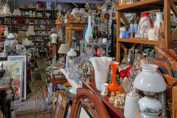 Large number of of multi colored antique, vintage, old, historic, knick knack, small collectables stacked on shelves and floor