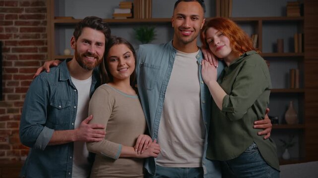 Group of multiracial people portrait four diverse multiethnic friends smiling carefree cheerful looking at camera in apartment home party men women hugging together friendship unity buddies positive
