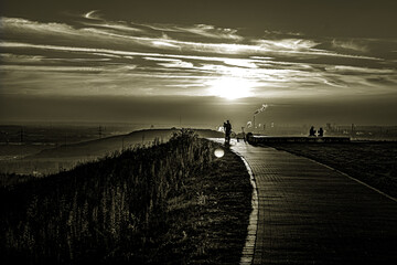 Wo der Himmel die Erde küsst, zieht sich ein Weg durch die Stille. In Sepia getaucht liegt diese Szene da wie eine alte Erinnerung – der Radfahrer ein einsamer Wanderer zwischen Tag und Nacht, die Sil