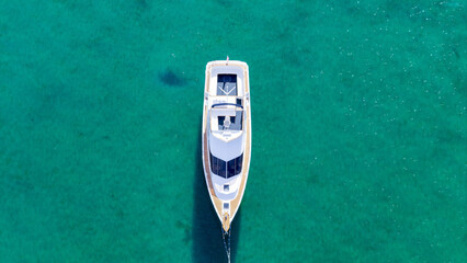 Aerial view of a lone white yacht cutting through the vibrant turquoise water, showcasing a stark contrast, Location data omitted.