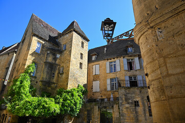 Visitors marvel at the stunning medieval architecture in Sarlat, Dordogne, with its characteristic stone buildings and intricate details under a clear blue sky.