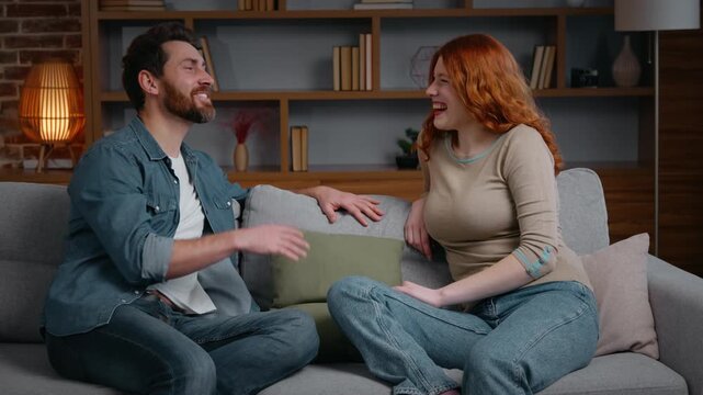 Caucasian happy smiling couple talking on couch at home emotional husband wife communicate man sharing good news with excited woman in living room friends spouses family girlfriend boyfriend laughing