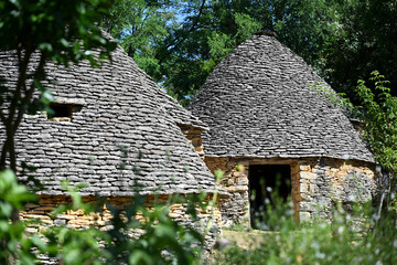 Nestled in the scenic Perigord Noir, ancient dry stone structures stand in Saint-Andre-d'Allas, reflecting the rich agricultural heritage of the Dordogne valley under a clear blue sky.