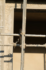 Close-up at metal pipe connection joint of the working platform scaffold at the house building work site. Industrial equipment and object, selective focus.