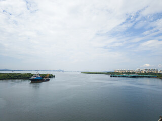 A panoramic Navi Mumbai travel view of boats in the city harbor and ships on the river under a blue sky, capturing the scenic coastal landscape of a Mumbai port