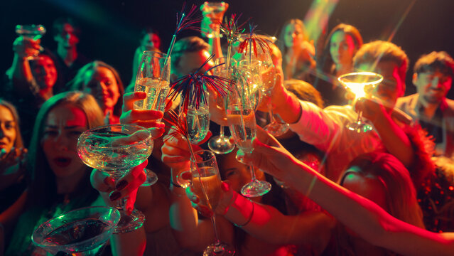 Glasses raised high for a neon-lit New Year celebration full of joy. Concept of alcohol brand promotion, nightlife advertising, emotional unity, and digital lifestyle