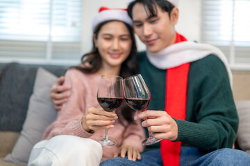 Asian couple celebrating christmas at home toasting red wine