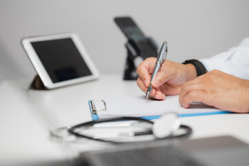 Doctor Writing Medical Report in Modern Office with Digital Devices