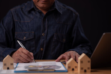 Man Signing Real Estate Contract with Money and House Models