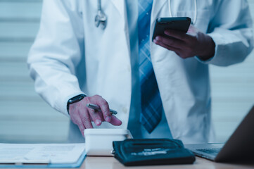 Doctor Working with Smartphone and Medical Equipment in Office