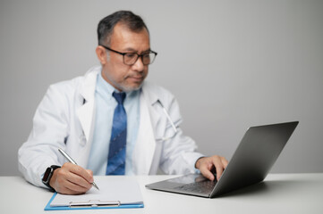Focused Doctor Working on Laptop and Notes in Medical Office