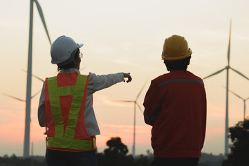 Engineers discussing wind turbine projects at sunset, showcasing renewable energy innovation and...