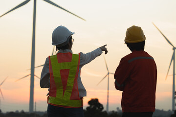 Engineers examining wind turbines at sunset, showcasing renewable energy advancements and sustainable technology.
