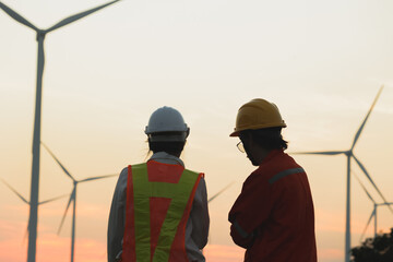 Two workers discuss renewable energy projects at a wind farm during sunset, showcasing dedication...