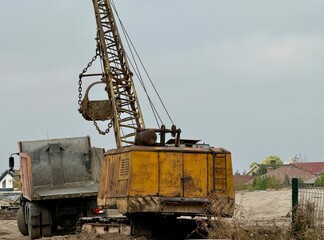 Old Excavator Loading Sand into Truck at Construction Site