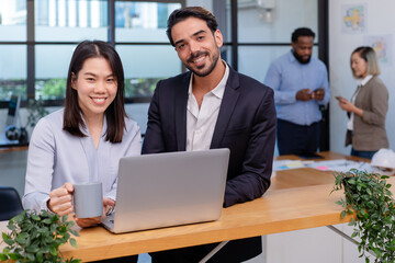 team of multiethnic colleague discuss business topic in creative green office co working space, group of business people coworker casual online meeting on laptop standing desk modern office workplace