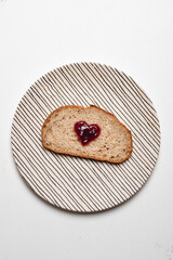 Slice of whole wheat sourdough bread with Heart Shaped Jam on Striped Plate