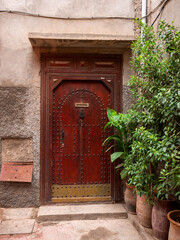 Ornate Wooden Doorway with Metal Studs and Traditional Potted Plants in a Marrakech Alley, Morocco