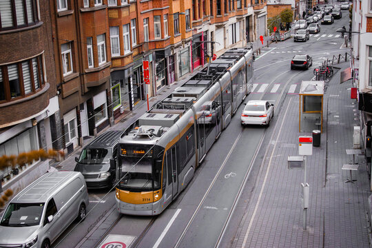 Top view of a European city street with tram tracks, modern tram, parked cars, brick buildings. Urban scene, city infrastructure, sustainable transport, streetscape, city life. - Powered by Adobe