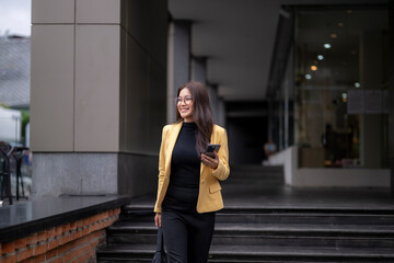 Smiling businesswoman walking down steps while holding smartphone