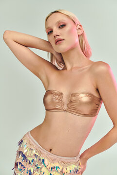 Fototapeta Young woman in stylish party outfit with holographic details in vibrant studio setting