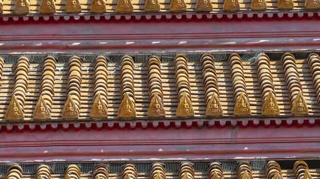 Roof decoration on the Uposatha Hall, Ubosot, the roof is staggered in three tiers and covered with rows of golden yellow glazed Chinese tiles, the last tile of each row at the eaves represents a heavenly angel offering the traditional Thai obeisance Wai to the viewer with folded hands, Wat Benchamabophit, marble temple, Bangkok, Thailand