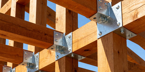 Modern timber framework construction with metal fasteners and bolts under clear sky, highlighting wood joinery and building structure
