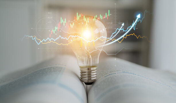 A light bulb sits atop an open book with financial graphs illuminated, symbolizing the fusion of knowledge and innovative ideas in the business world. Scalp