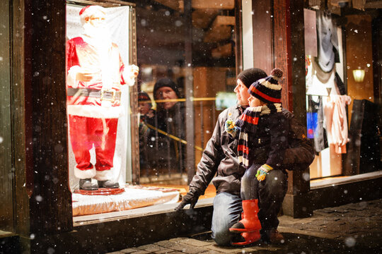 Little toddler boy with father on Christmas market. Funny happy kid making window shopping with Santa Claus. holidays, christmas, childhood and people concept. family during winter snowfall