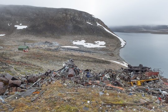 Scrapyard in rocky coastal landscape with snow remains, arctic settlement Ittoqqortoormiit, Scoresbysund or Scoresby Sund or Greenlandic Kangertittivaq, East Greenland, Greenland