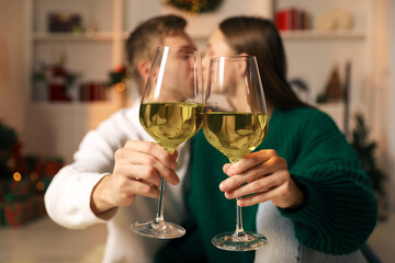 Lovely couple with glasses of wine in festive decorated room, selective focus