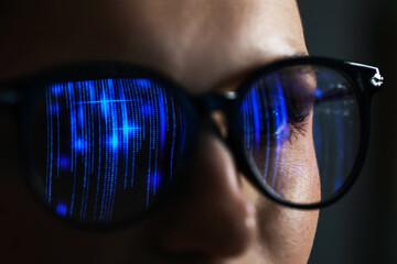 Young woman wearing glasses with reflection on dark background, closeup