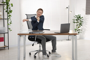 Young businessman stretching his arm at table in office
