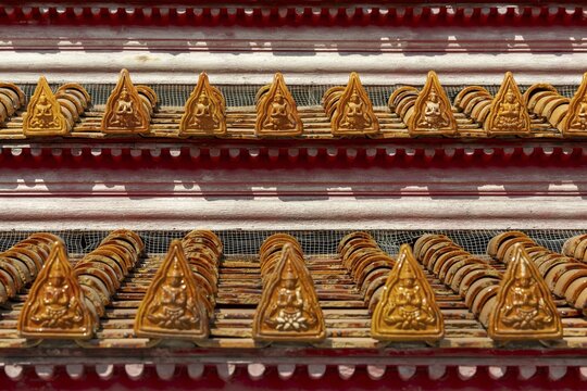 Roof decoration at the Uposatha Hall, Ubosot, the roof is staggered in three tiers and covered with rows of golden yellow glazed Chinese tiles, the last tile of each row at the eaves represents a heavenly angel offering the traditional Thai obeisance Wai to the viewer with folded hands, Wat Benchamabophit, marble temple, Bangkok, Thailand
