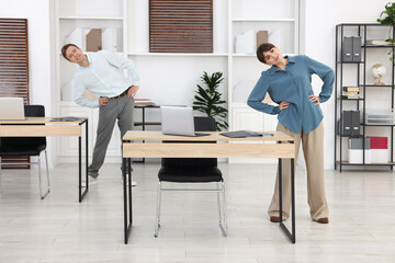 Man and woman doing stretching exercise in office