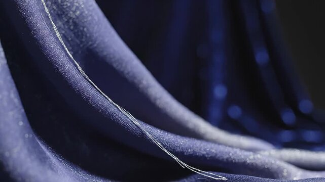 A blue fabric with silver thread in a flowing drapery