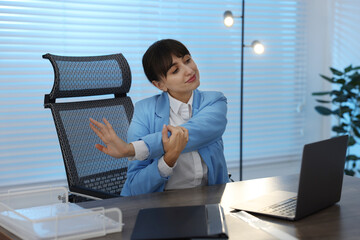 Young businesswoman stretching her arm at table in office