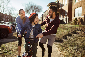 Young family teaching son to ride bike