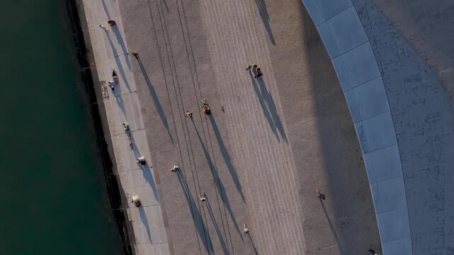 Top-down aerial view of people walking along the riverfront and the rooftop of Maat museum 