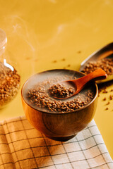Buckwheat groats cooking in a wooden bowl with steam rising in a cozy kitchen setting