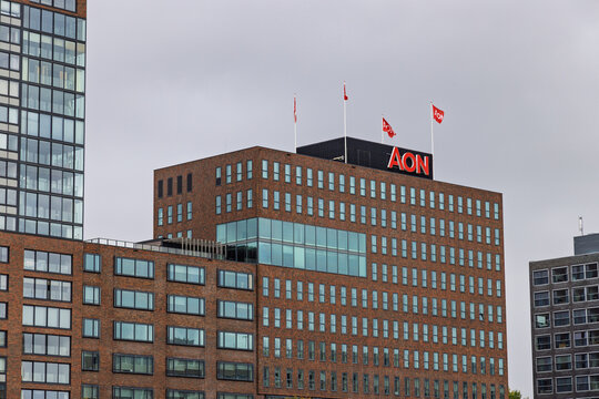 The Aon building in Rotterdam, Netherlands, a modern brick-clad office high-rise with a distinctive red AON logo and flags flying on the rooftop. Rotterdam, Netherlands. 5 October 2025.