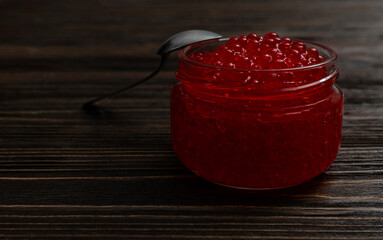Red Caviar in Glass Jar on Dark Wooden Background