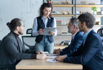 Happy middle aged business woman discussing project management working with colleagues company team at office