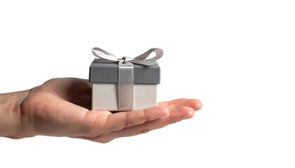 Obraz premium A hand holds a beautifully wrapped gift box with a ribbon on top. The box is presented, conveying the act of giving. 