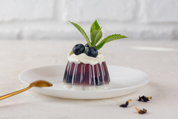 Jelly dessert with anchan tea, blueberries, mint and coconut cream on a white plate with golden...