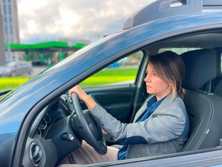 Naklejka premium Side view of Caucasian beautiful busy businesswoman driving a car. Close up of pretty attractive successful lady sitting inside the vehicle looking at road. Business lifestyle