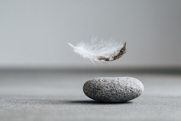White feather floating above smooth stone minimalistic composition soft light calm atmosphere balance tranquility peaceful zen natural elements simplicity