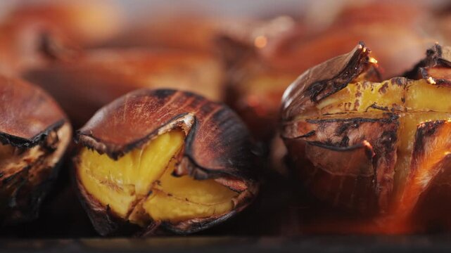 Grilled Fresh chestnut, supermarket food, grill Oven roasted chestnuts with sliced peel on wooden board, spanish traditional winter dish.