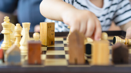 Child playing chess with wooden house models, representing real estate education, inheritance planning, legacy transfer, future investment, and building family wealth.